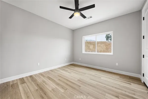a view of empty room with wooden floor and ceiling fan
