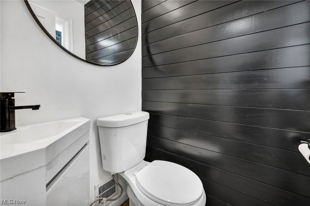 932 Englewood Road Cleveland Heights, OH 44121 - Photo 25 of 32 Bathroom with wooden walls, vanity, and toilet