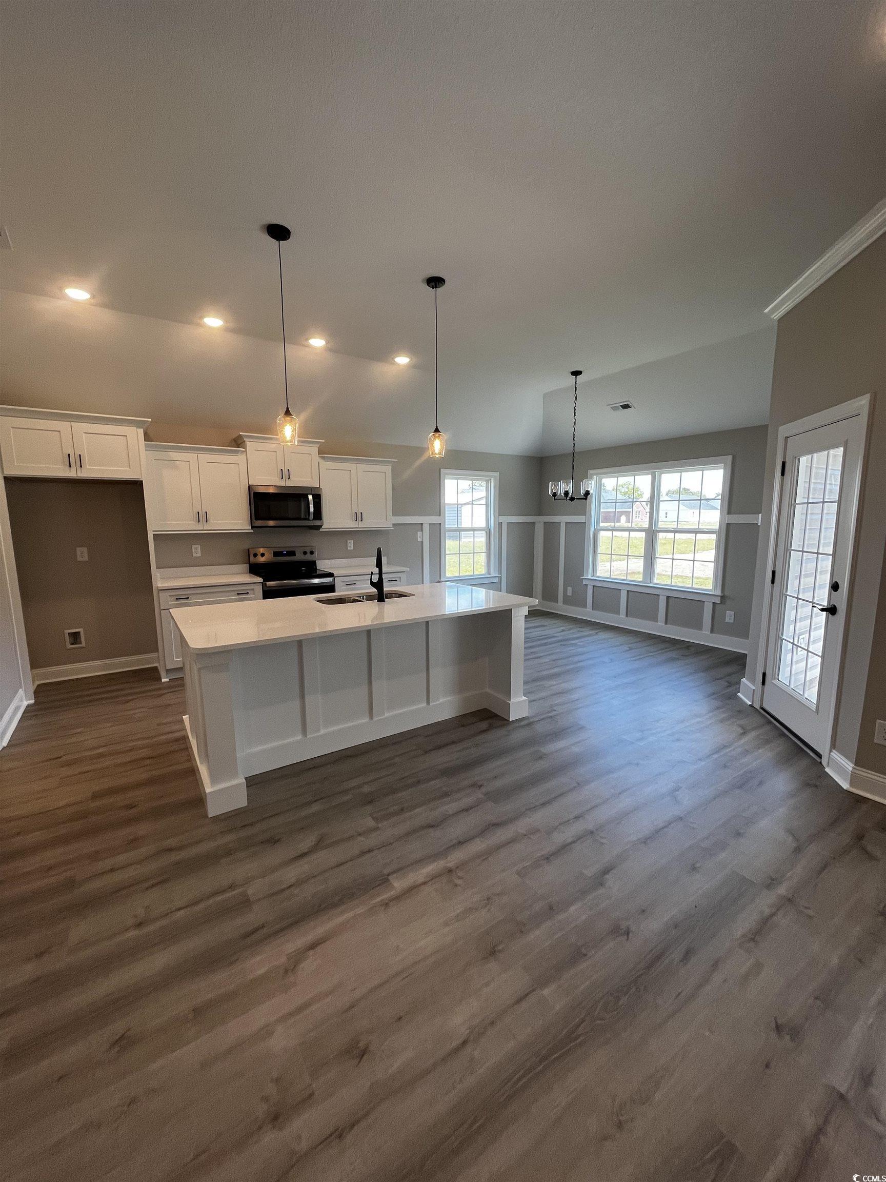 3530 Good Luck Road Aynor, SC 29511 - Photo 3 of 8 Kitchen with a kitchen island with sink, white cabinetry, pendant lighting, appliances with stainless steel finishes, and a kitchen breakfast bar