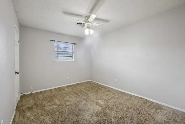 an empty room with a fan & a window