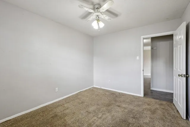an empty room with a chandelier fan and closet area