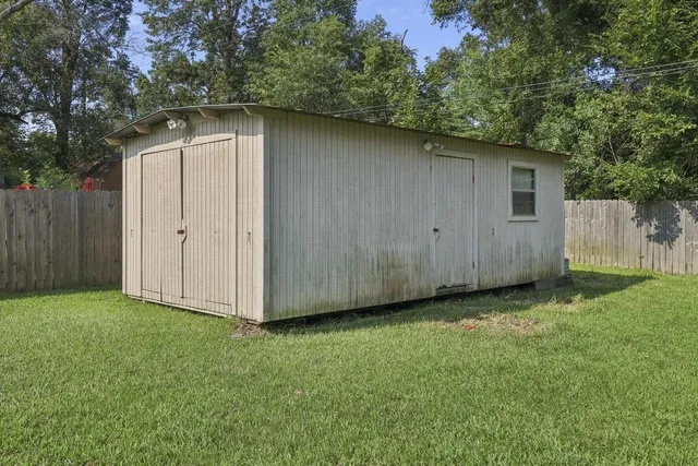 a backyard of a house with large trees and wooden fence