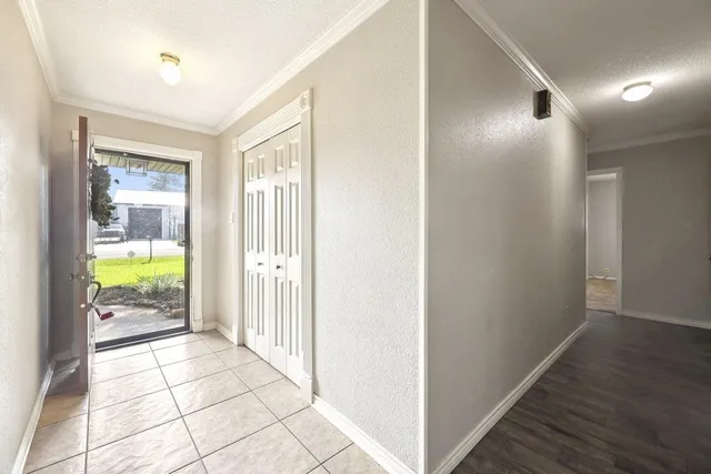 a view of a hallway to a livingroom with a dining table & chairs