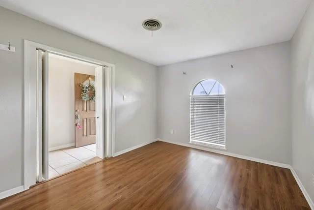 an empty room with wooden floor and windows