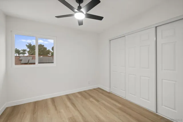 a view of empty room with wooden floor and fan