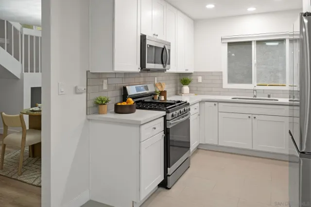 a kitchen with stainless steel appliances granite countertop a stove a sink and a microwave