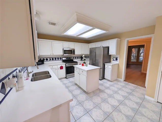 a kitchen with a sink a counter top space cabinets and stainless steel appliances