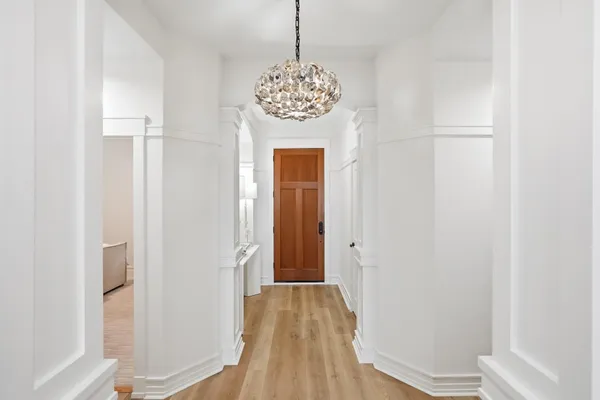 a view of a hallway with wooden floor and chandelier