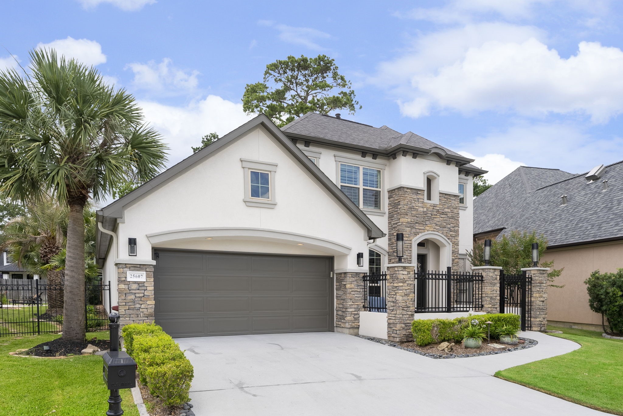 25607 Muirfield Bend Court Spring, TX 77389 - Photo 2 of 30 Beautifully appointed patio home featuring rich stone accents, a welcoming gated courtyard, lush landscaping, and sophisticated architectural elements that enhance its exceptional curb appeal.