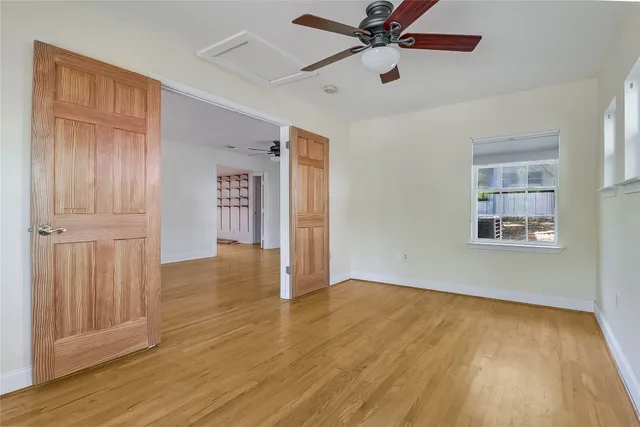 an empty room with wooden floor closet and windows