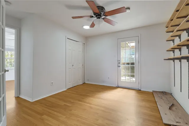 an empty room with windows and fan