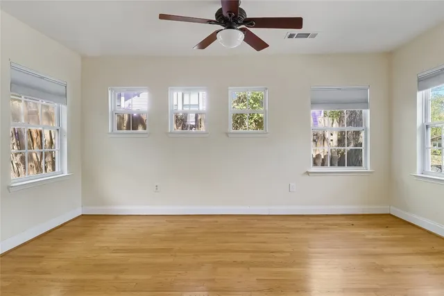 a view of an empty room with window and wooden floor