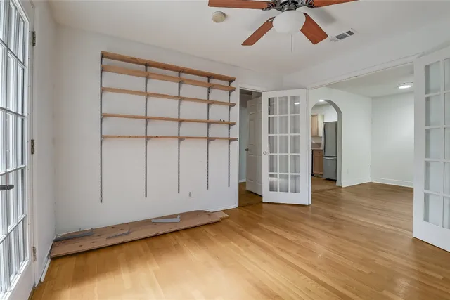 a view of empty room with wooden floor and fan