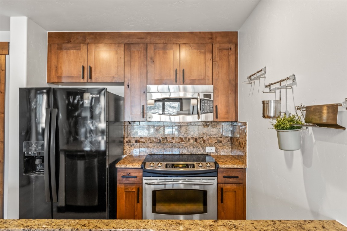 1175 Bangtail Way, Unit 2106 Steamboat Springs, CO 80487 - Photo 11 of 32 a kitchen with stainless steel appliances granite countertop a stove a refrigerator and a microwave