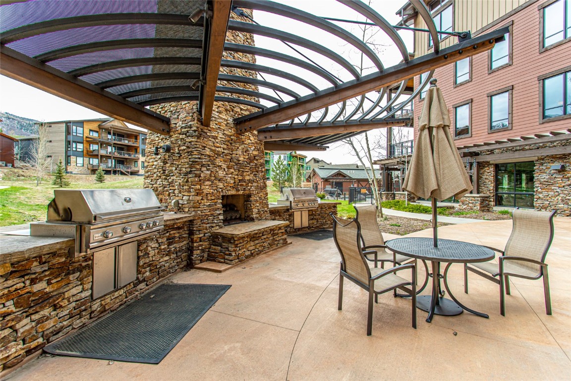 1175 Bangtail Way, Unit 2106 Steamboat Springs, CO 80487 - Photo 21 of 32 a view of a chairs and table in the patio with a barbeque