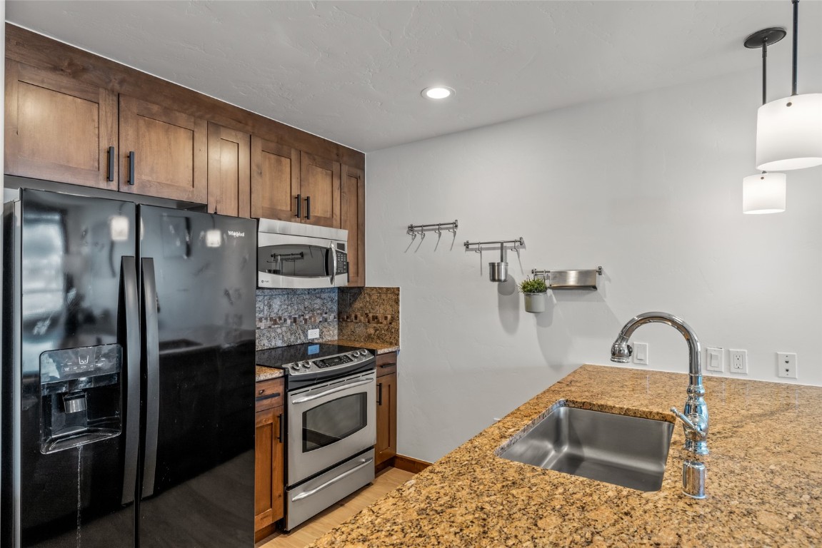 1175 Bangtail Way, Unit 2106 Steamboat Springs, CO 80487 - Photo 9 of 32 a kitchen with stainless steel appliances granite countertop a refrigerator sink and stove
