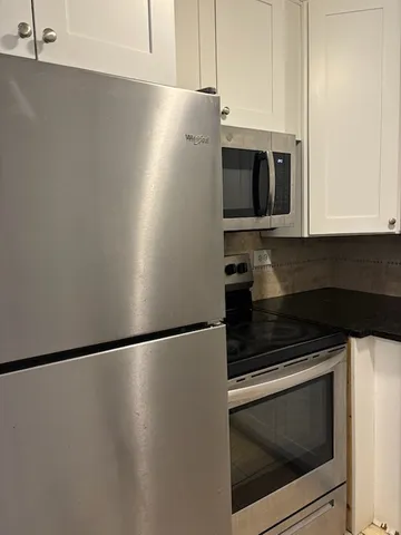 a kitchen with stainless steel appliances white cabinets and a microwave oven