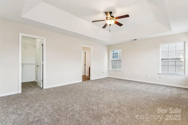 a view of an empty room with a ceiling fan and window