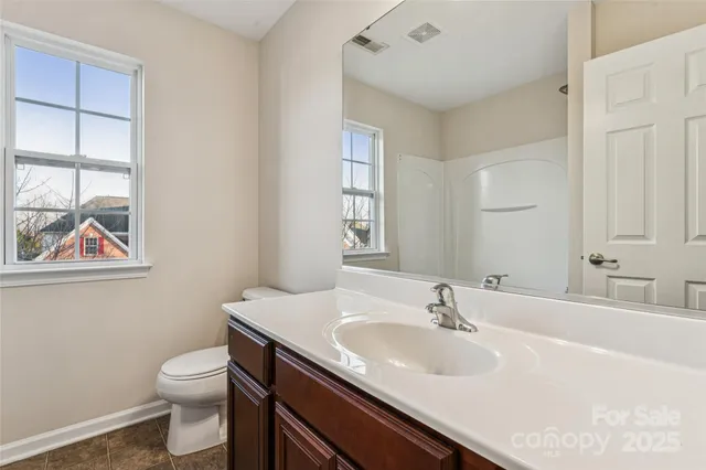 a bathroom with a toilet a sink a mirror and a window