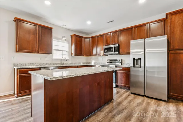 a kitchen with granite countertop a refrigerator stove top oven and sink