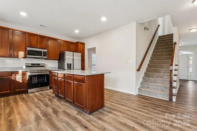 a large kitchen with wooden floors and stainless steel appliances