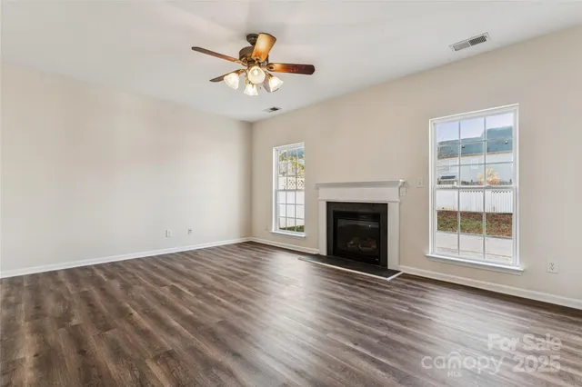 an empty room with windows fireplace and wooden floor