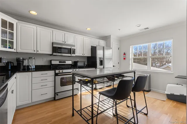 a kitchen with stainless steel appliances granite countertop a stove a sink dishwasher a microwave oven with white cabinets and wooden floor