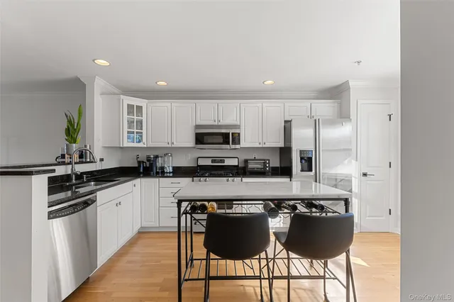 a kitchen with stainless steel appliances granite countertop a stove a sink a microwave a refrigerator and white cabinets