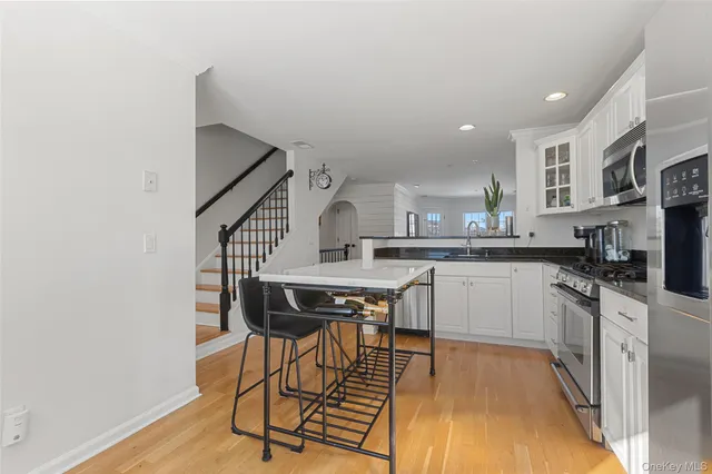 a kitchen with stainless steel appliances kitchen island a table chairs in it and wooden floors