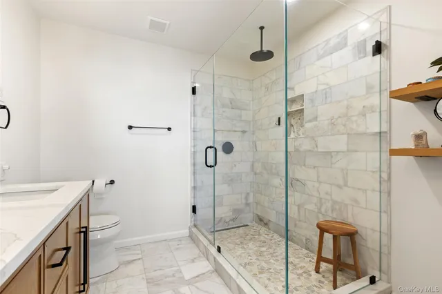 a bathroom with a granite countertop shower a toilet and a sink