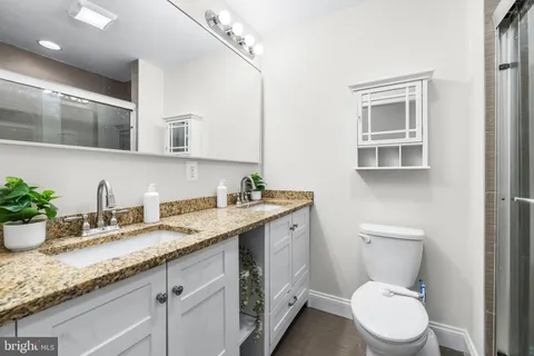 a bathroom with a granite countertop toilet sink and mirror
