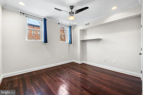 an empty room with wooden floor and ceiling fan