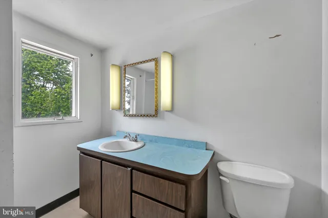 a bathroom with a toilet a sink a window and mirror