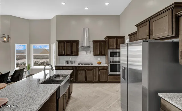 a kitchen with stainless steel appliances granite countertop a refrigerator a stove a sink and a microwave