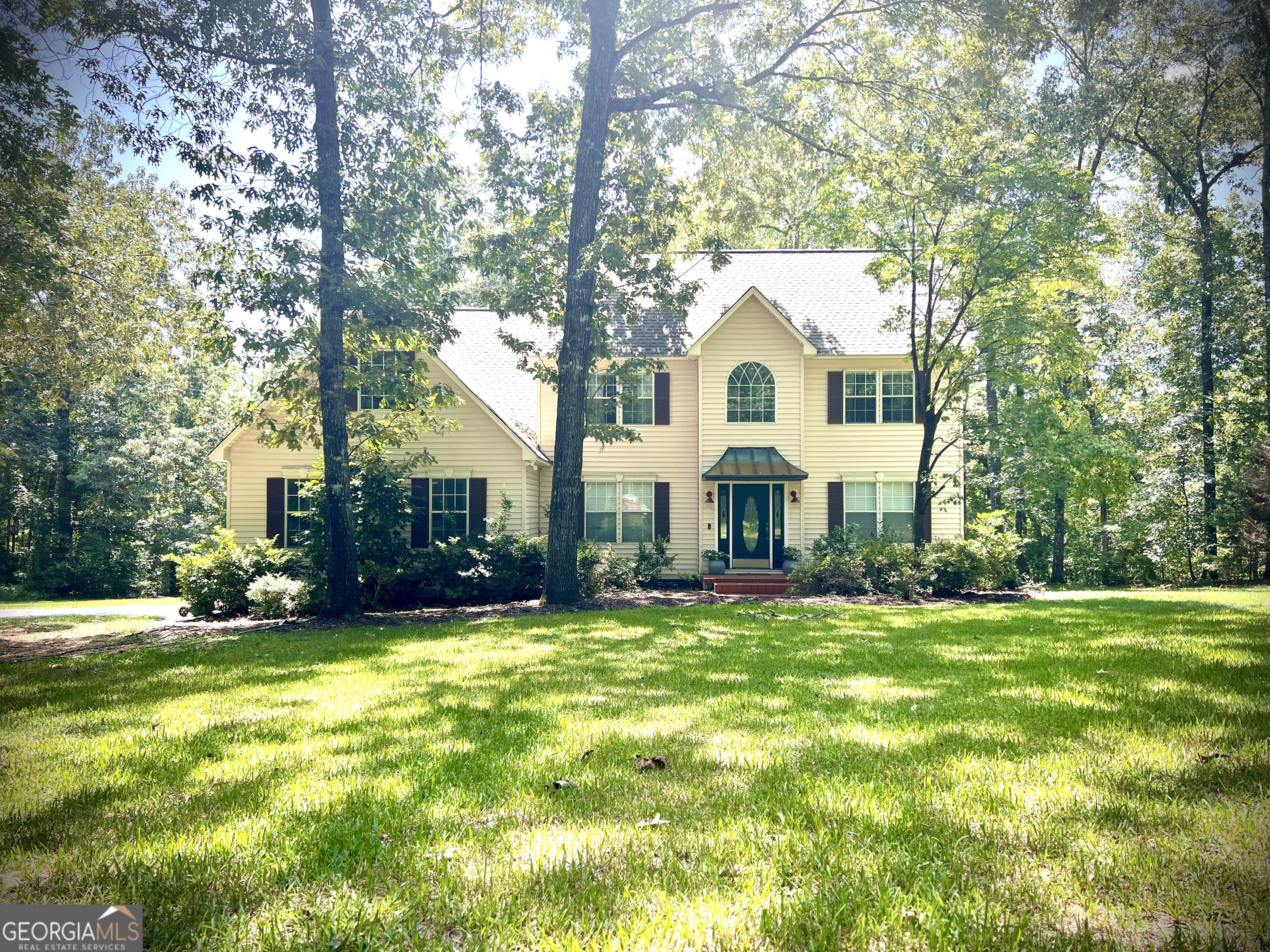 a front view of a house with a garden and trees