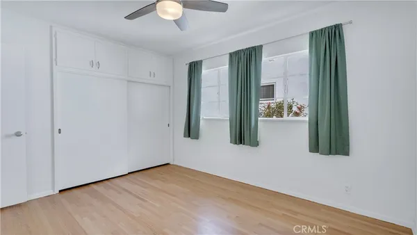 a view of a livingroom with wooden floor a ceiling fan and windows
