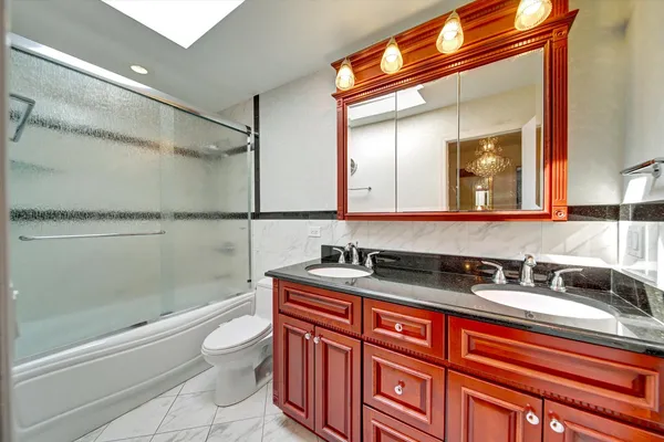 a bathroom with a granite countertop sink a toilet a mirror and shower