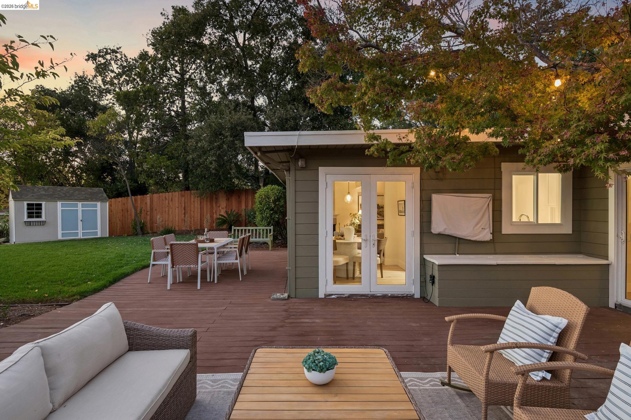 1321 Sunset Loop Lafayette, CA 94549 - Photo 43 of 49 Expansive wood-finish deck with French doors, a built-in outdoor storage bench, and a grass lawn with a storage shed