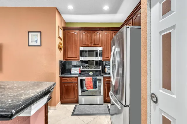 a kitchen with stainless steel appliances granite countertop a refrigerator and a stove top oven