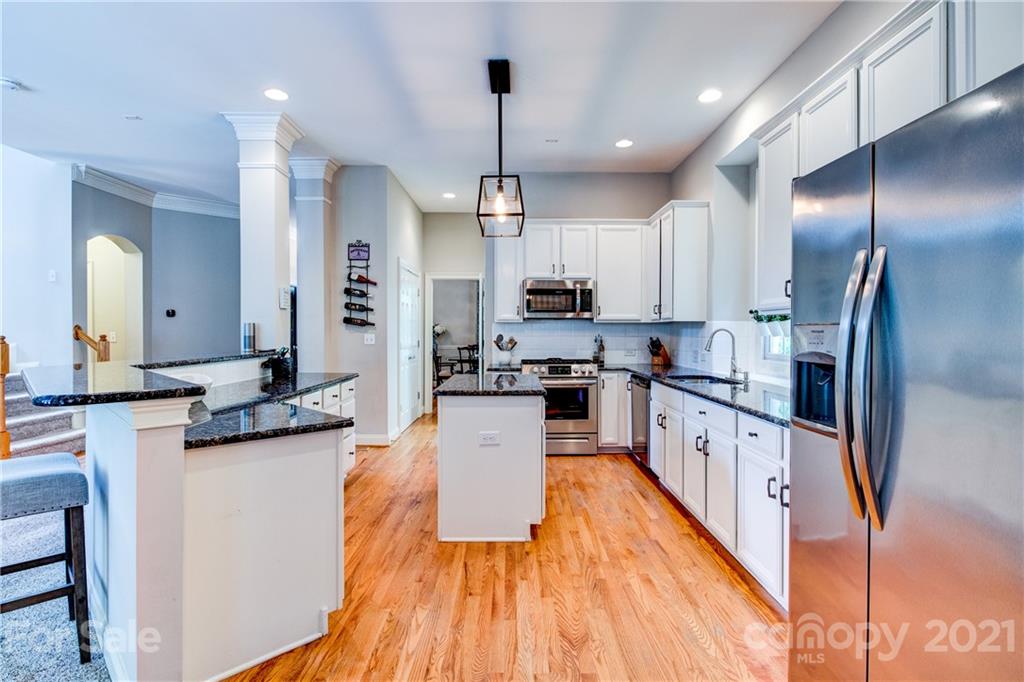 7155 Michael Scott Crossing Fort Mill, SC 29708 - Photo 13 of 41 a kitchen with stainless steel appliances granite countertop a refrigerator a stove top oven a sink dishwasher and wooden cabinets with wooden floor