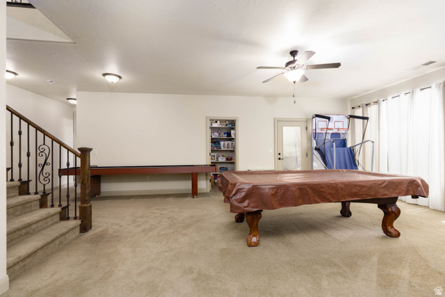 2005 West 450 S Circle St. George, UT 84770 - Photo 26 of 57 Spacious open area featuring neutral carpet flooring, a staircase with wrought iron balusters, and a ceiling fan with integrated lighting