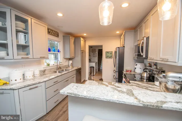 a large kitchen with granite countertop a sink stainless steel appliances and cabinets