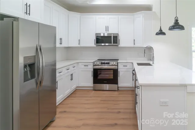 a kitchen with stainless steel appliances granite countertop a refrigerator a stove and a sink with wooden floor