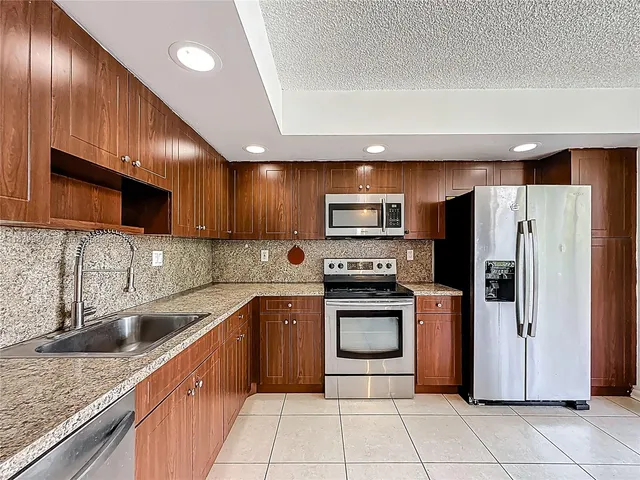 a kitchen with stainless steel appliances granite countertop a sink dishwasher stove top oven and refrigerator