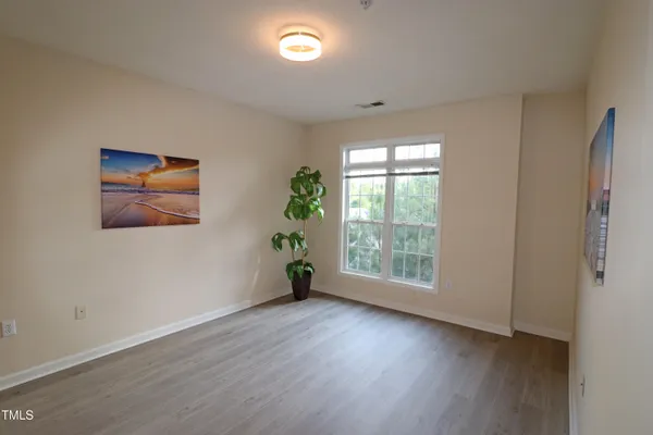an empty room with wooden floor and window