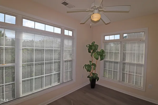 a view of an empty room with a window and wooden floor