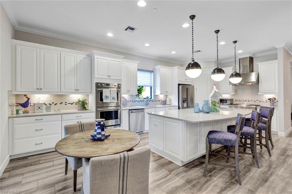 10163 Coconut Road Estero, FL 34135 - Photo 11 of 44 a kitchen with stainless steel appliances kitchen island granite countertop a table chairs and a sink