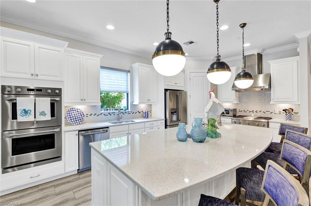 10163 Coconut Road Estero, FL 34135 - Photo 13 of 44 a kitchen with kitchen island granite countertop a stove a oven a dining table and chairs with wooden floor