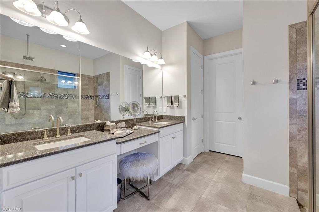 10163 Coconut Road Estero, FL 34135 - Photo 19 of 44 a bathroom with a granite countertop double vanity sink a mirror and a shower