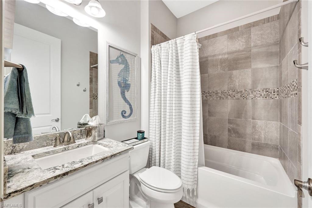 10163 Coconut Road Estero, FL 34135 - Photo 26 of 44 a bathroom with a granite countertop sink toilet mirror and bathtub